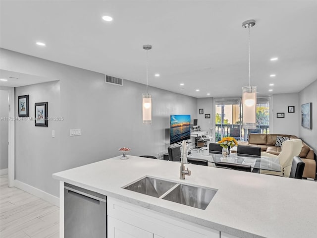 kitchen with decorative light fixtures, dishwasher, white cabinetry, and sink