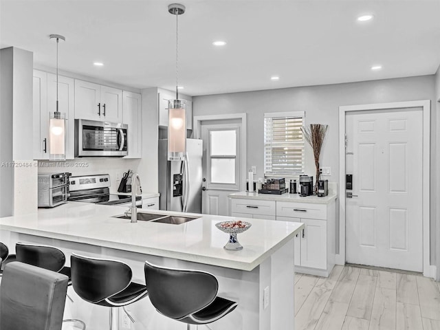 kitchen with a kitchen breakfast bar, white cabinetry, pendant lighting, and stainless steel appliances