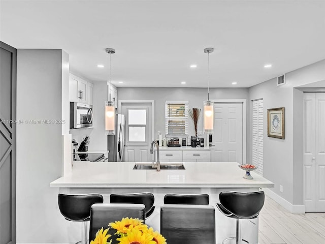 kitchen with pendant lighting, a kitchen breakfast bar, sink, appliances with stainless steel finishes, and kitchen peninsula