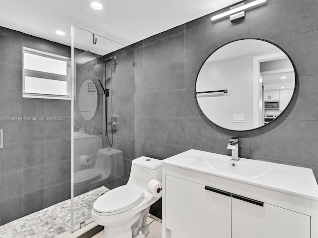 bathroom with vanity, a shower with shower door, tile walls, and toilet