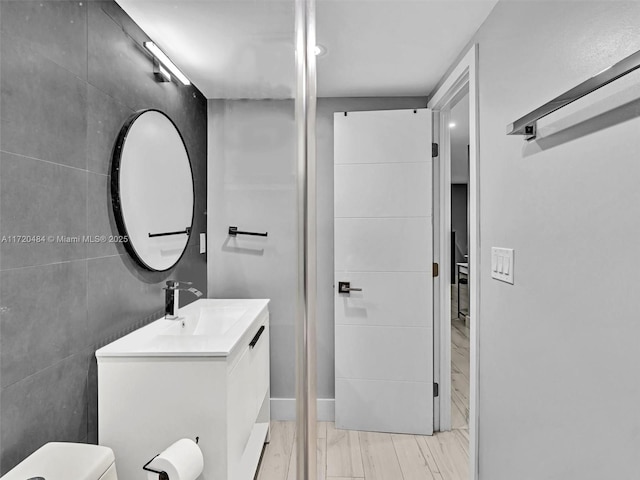 bathroom with vanity, toilet, and tile walls