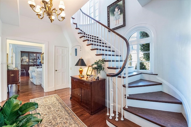 staircase with hardwood / wood-style floors and a notable chandelier