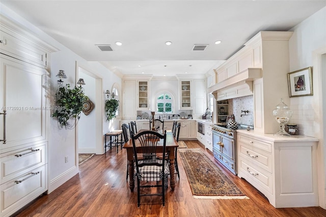 kitchen with backsplash, white cabinets, stainless steel stove, dark hardwood / wood-style flooring, and light stone counters