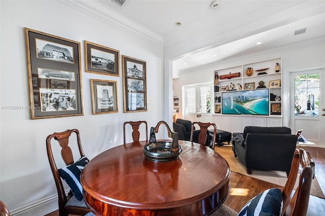 dining room featuring hardwood / wood-style floors, built in features, and ornamental molding