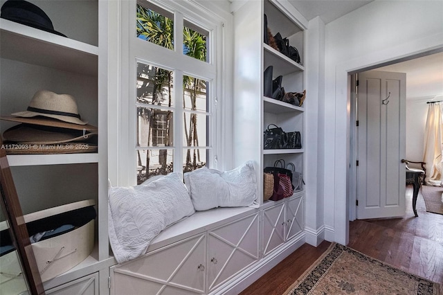 mudroom with built in shelves and dark wood-type flooring