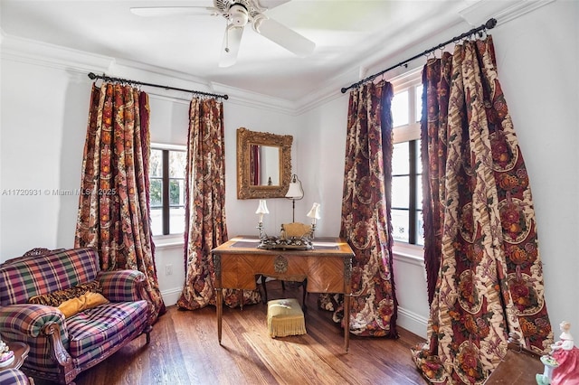 living area with wood-type flooring, a wealth of natural light, ceiling fan, and crown molding