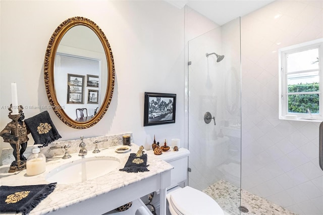 bathroom with tiled shower, vanity, and toilet