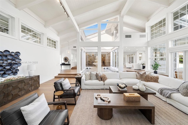 living room with hardwood / wood-style floors, track lighting, high vaulted ceiling, and beam ceiling