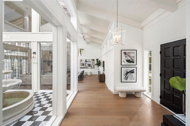 entryway with beam ceiling, high vaulted ceiling, light hardwood / wood-style floors, and a notable chandelier