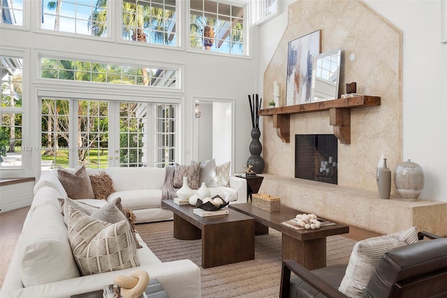 living room featuring a towering ceiling, french doors, a high end fireplace, and wood-type flooring