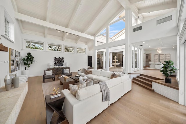 living room with a wealth of natural light, beamed ceiling, high vaulted ceiling, and light wood-type flooring