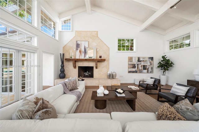 living room featuring beam ceiling, a fireplace, hardwood / wood-style floors, and a towering ceiling