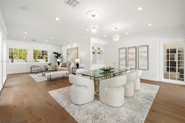 dining room with wood-type flooring, crown molding, and an inviting chandelier