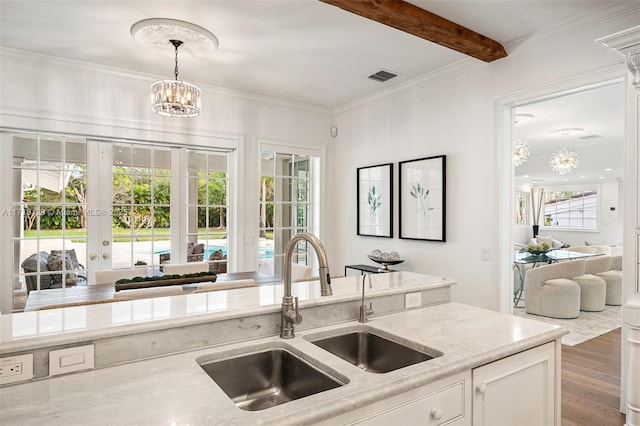 kitchen with pendant lighting, an inviting chandelier, wood-type flooring, sink, and white cabinetry