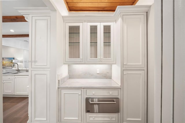 interior space featuring white cabinetry, sink, beamed ceiling, and hardwood / wood-style floors