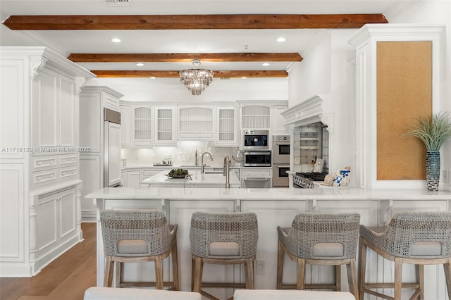 kitchen with beam ceiling, white cabinetry, a kitchen breakfast bar, dark hardwood / wood-style floors, and a chandelier