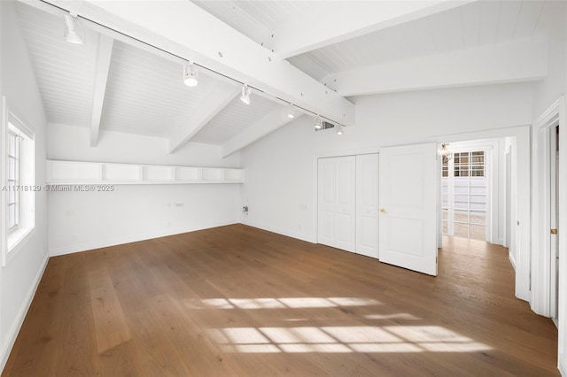 additional living space featuring hardwood / wood-style flooring, lofted ceiling with beams, and a healthy amount of sunlight