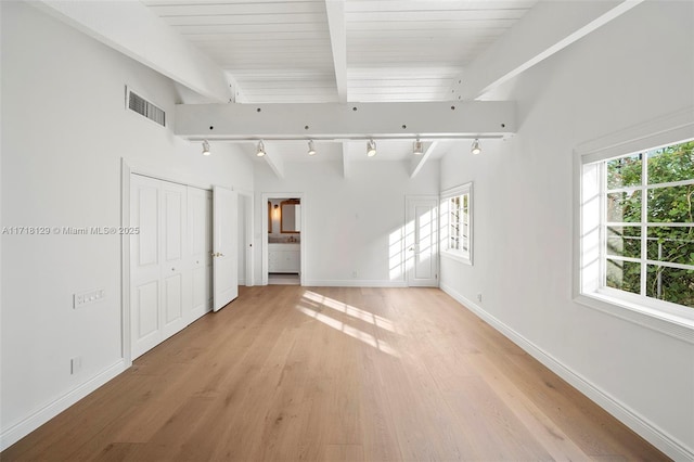 empty room with beamed ceiling, rail lighting, and plenty of natural light