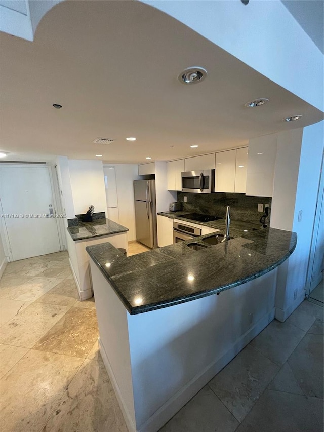 kitchen with white cabinetry, kitchen peninsula, appliances with stainless steel finishes, and tasteful backsplash