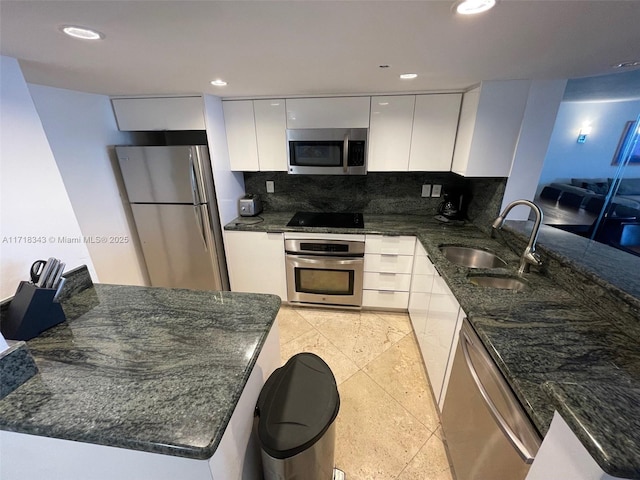 kitchen with sink, stainless steel appliances, dark stone counters, decorative backsplash, and white cabinets