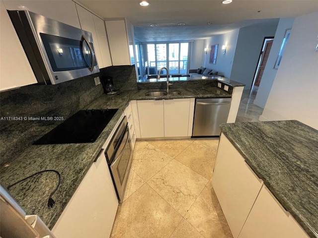 kitchen featuring white cabinets, sink, stainless steel appliances, and dark stone counters