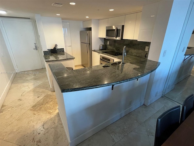 kitchen featuring white cabinets, kitchen peninsula, sink, and appliances with stainless steel finishes