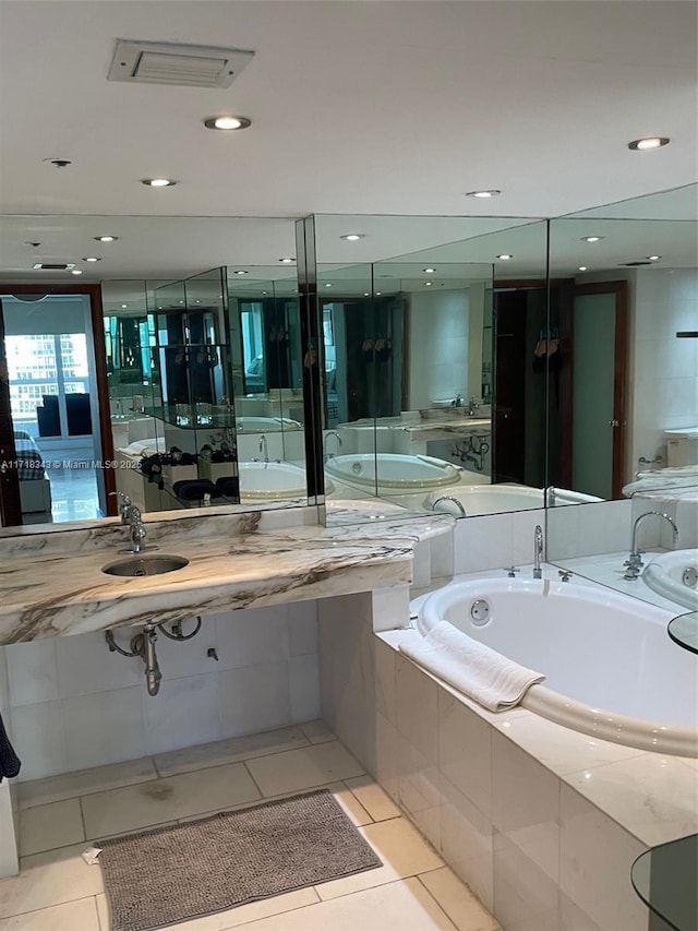 bathroom with tile patterned flooring, sink, and tiled tub