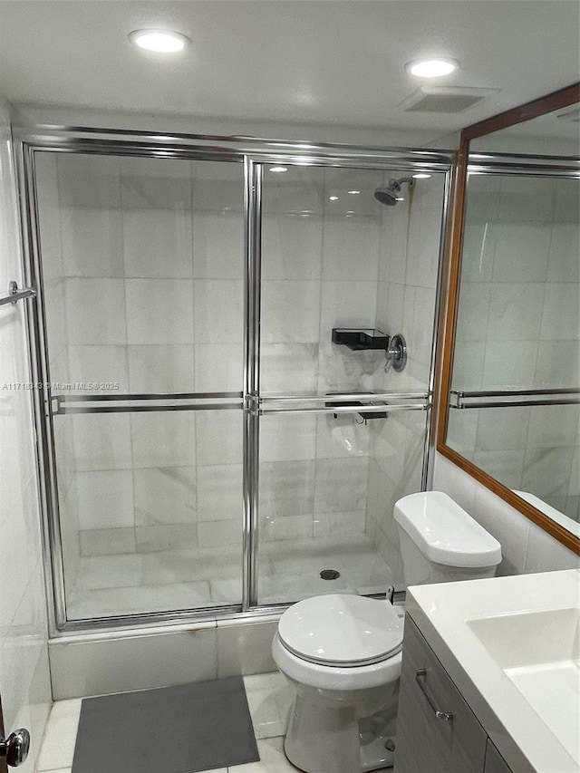 bathroom with tile patterned flooring, vanity, a shower with door, and toilet