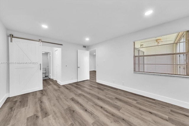 spare room featuring a barn door and light wood-type flooring