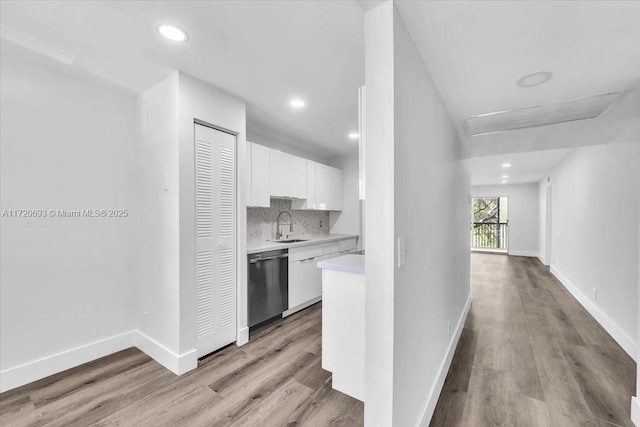 kitchen featuring white cabinetry, dishwasher, sink, backsplash, and light wood-type flooring