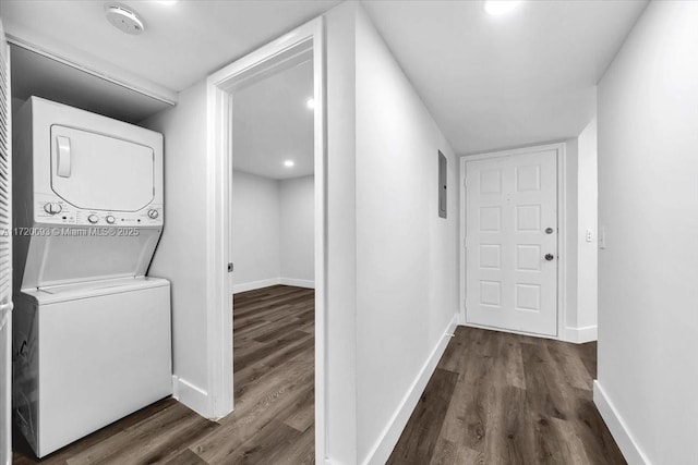 washroom with stacked washer and dryer and dark wood-type flooring