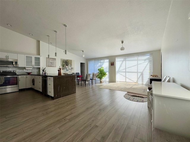 kitchen with dark hardwood / wood-style floors, pendant lighting, lofted ceiling, white cabinets, and appliances with stainless steel finishes