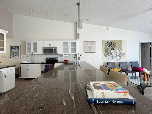 kitchen with decorative backsplash, black range with electric stovetop, sink, pendant lighting, and white cabinetry