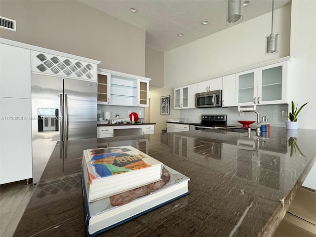 kitchen featuring kitchen peninsula, appliances with stainless steel finishes, sink, a high ceiling, and white cabinetry