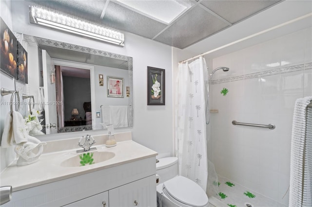 bathroom with curtained shower, a drop ceiling, vanity, and toilet