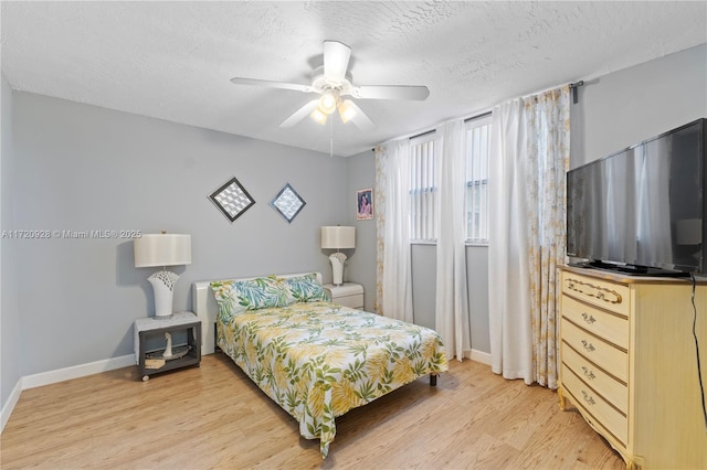 bedroom with ceiling fan, light hardwood / wood-style floors, and a textured ceiling