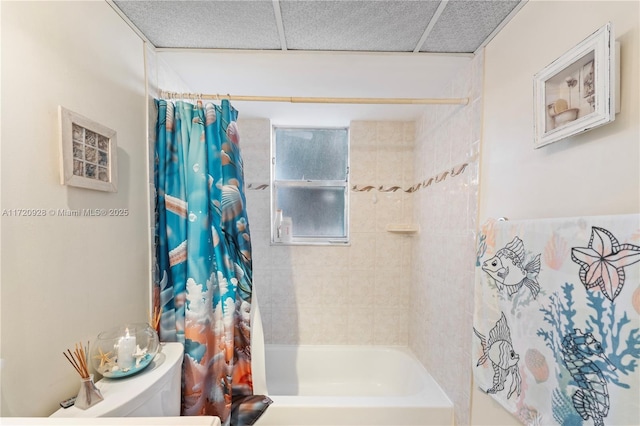 bathroom featuring a drop ceiling, toilet, and shower / bath combo with shower curtain