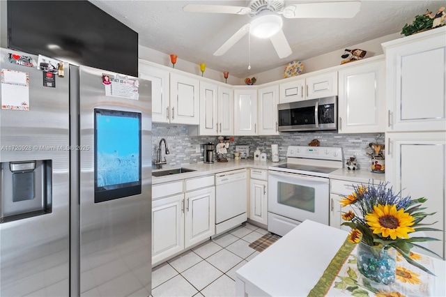 kitchen with sink, stainless steel appliances, white cabinets, backsplash, and light tile patterned flooring