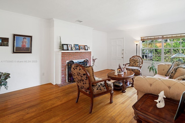 living room featuring hardwood / wood-style flooring, a fireplace, and crown molding