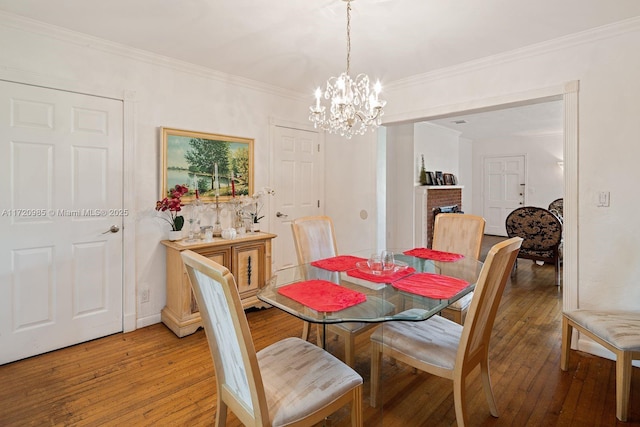 dining area with hardwood / wood-style floors, ornamental molding, and an inviting chandelier