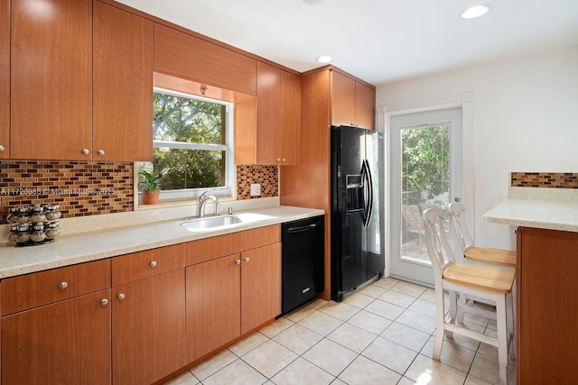 kitchen featuring backsplash, sink, light tile patterned floors, and black appliances