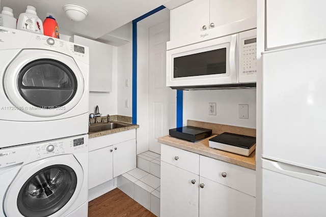 clothes washing area with hardwood / wood-style flooring, stacked washer / dryer, and sink