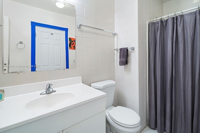 bathroom with curtained shower, vanity, tile walls, and toilet