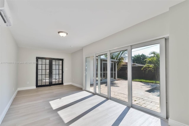 doorway to outside featuring french doors, a wall mounted AC, light wood-type flooring, and baseboards