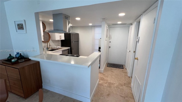 kitchen featuring visible vents, a sink, freestanding refrigerator, ventilation hood, and light countertops