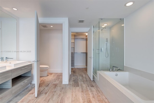 full bathroom with toilet, wood-type flooring, vanity, and separate shower and tub