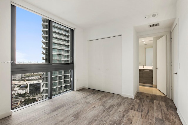 unfurnished bedroom with hardwood / wood-style flooring, a wall of windows, and multiple windows