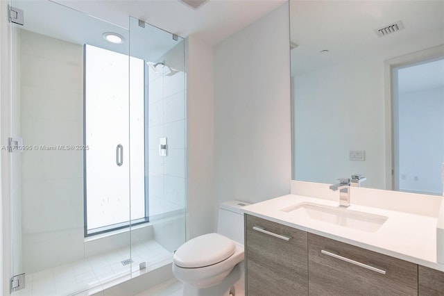 bathroom featuring vanity, toilet, and a shower with door