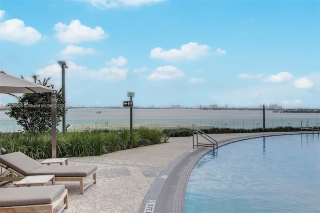 view of swimming pool featuring a water view and a patio