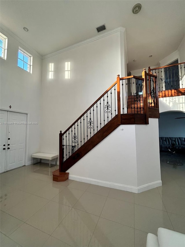 staircase featuring tile patterned flooring, lofted ceiling, and crown molding